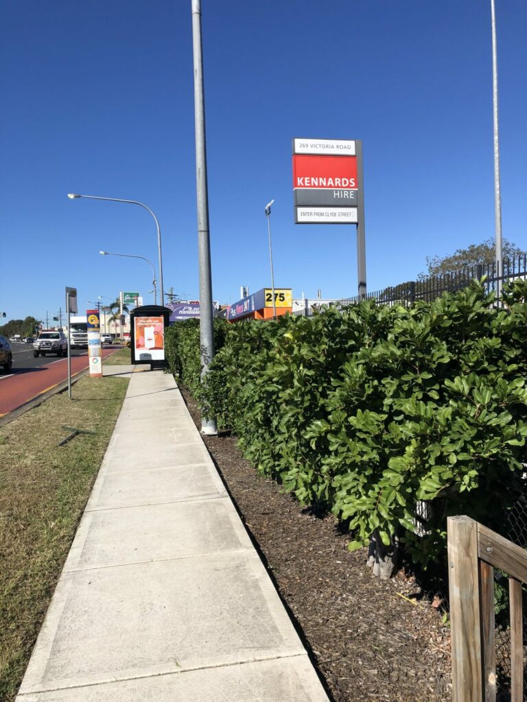 The same roadside hedge after trimming, cut to a level line along the footpath with the path swept clean